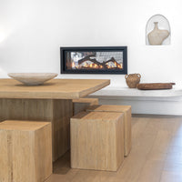 Solid timber dining table paired with matching block-style stools, styled with a textured ceramic bowl, Vase, and hand-carved wooden tray, set against a modern fireplace for a warm and inviting dining space