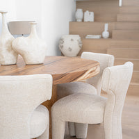 A luxurious dining setting featuring a solid wood live-edge dining table paired with sculptural boucle dining chairs. The organic textures and soft neutral tones create a warm, contemporary aesthetic