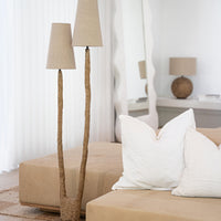 A sculptural twin floor lamp with textured paper mache stems and natural linen shades, styled in a serene living space with neutral-toned furnishings and organic textures. The perfect statement piece for modern, nature-inspired interiors