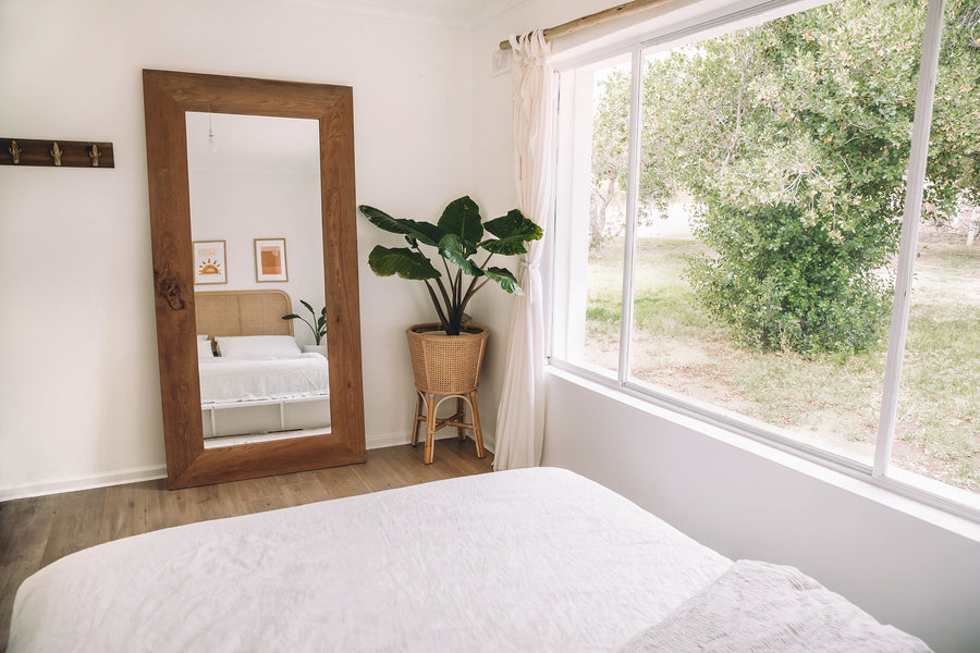 Uniqwa Collections Nature Weathered Mirror styled in a coastal bedroom with neutral tones, rattan accents, and natural textures.